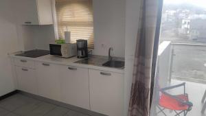 a small kitchen with a sink and a microwave at Apartamento T1 - Hotel Las Rochas in Mindelo