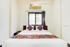 um quarto com uma grande cama branca com almofadas coloridas em Via Sahil Residency em Pune