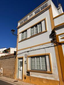 a white building with windows on a street at Casa Mira in Odemira