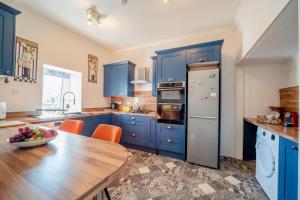 una cocina con armarios azules y una mesa con un bol de fruta en Annandale House, en Moffat