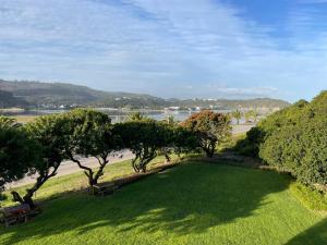 a park with benches and trees and a body of water at Suiderkruis Lodge in Groot Brak Rivier +24 photos
