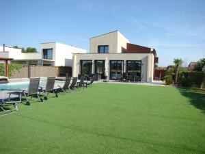 a lawn with chairs and a pool in front of a house at Villa en el campo cerca de la playa in Armentera