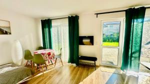 a bedroom with a table and green curtains and a bed at Domki Pasieka Domek D in Przeczyce