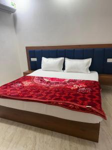 - un lit avec une couverture rouge dans l'établissement Radha Krishna Dham, à Mathura