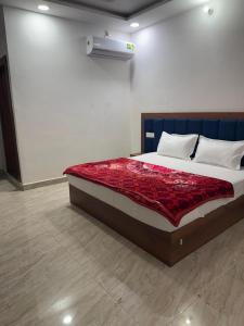 une chambre avec un lit avec une couverture rouge dessus dans l'établissement Radha Krishna Dham, à Mathura