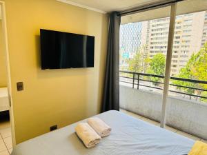 a bedroom with a flat screen tv and a bed with towels at Estancia para 3 cerca de Metro in El Cerrillo