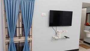 a living room with blue curtains and a tv at Tamil Homestay with Kitchen in Thanjāvūr