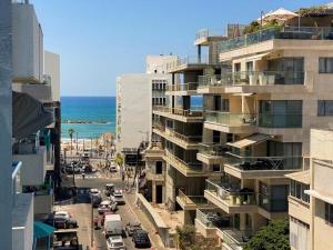 a tall building on a street next to the ocean at Sea View Duplex On Frishman Beach 2Bdr apt and BBQ in Tel Aviv