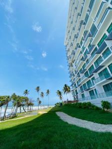 a large building next to a beach with palm trees at Sea & Turtles Galle condo in Galle