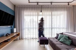 a person standing in a living room looking out the window at Charlie Itaim in Sao Paulo