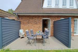 a patio with a table and chairs on a deck at Ferienwohnung Strandläufer Dagebüll in Dagebüll