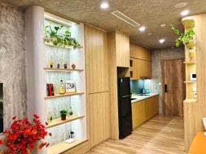 a kitchen with wooden cabinets and a black refrigerator at An An Homestay- Ecopark- Văn Giang- Hưng Yên in HÆ°ng YÃªn