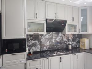 a kitchen with white cabinets and black counter tops at Sumeras Sapphire Retreat in Ajman 