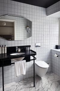 a white tiled bathroom with a sink and a toilet at Boutique Hotel Danmark in Copenhagen +47 photos
