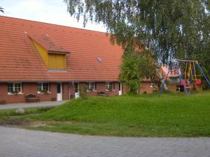 a red roofed building with a playground and a swing at Pferdehof Ruhnau in Potzlow