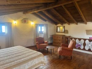 a bedroom with a bed and two chairs and a dresser at Casa Mercedes in El Río +9 photos