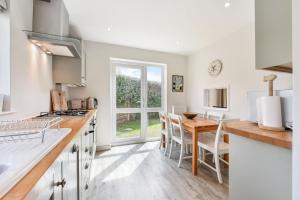 a kitchen with white cabinets and a table with chairs at 21 Owers Way, West Wittering in West Wittering +18 photos