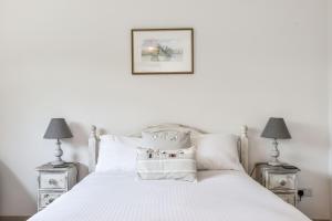 a bedroom with a white bed with two lamps at 21 Owers Way, West Wittering in West Wittering