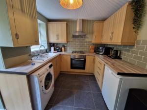 a kitchen with wooden cabinets and a washer and dryer at Chic 2 Bedroom Close to Town with Free Parking in Tredegar
