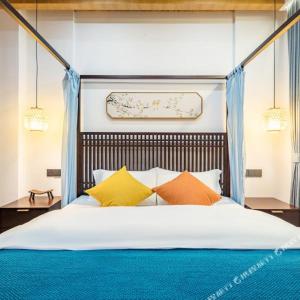 a bedroom with a large bed with colorful pillows at Floral Zhujiajiantuan Muting B&B in Zhoushan +2 photos