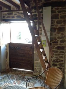 a wooden ladder in a room with a chair and a window at La Cahute, gîte étape in La Forêt-Auvray