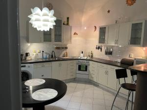 een keuken met witte kasten, een tafel en een kroonluchter bij Apartmán LACRON Praha in Praag