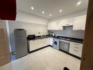 a kitchen with white cabinets and a washer and dryer at Jardin Yves Chic 2 bedrooms - AC - Parking in Marrakesh