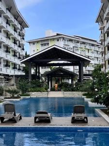 a swimming pool with lounge chairs in front of a building at Layover Stays 3 mins to Cebu Mactan Airport with Pool and Gym in Pusok