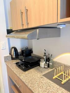a kitchen counter with a stove with a pan on it at Layover Stays 3 mins to Cebu Mactan Airport with Pool and Gym in Pusok