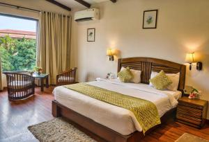 a bedroom with a bed and a table and a window at Sunday Alaya Resort by CheckIn, Jim Corbett in Belparāo +42 photos