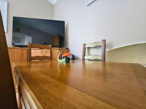 a large wooden table with a tv and two chairs at Le Jardin Edgar Malakoff in Malakoff