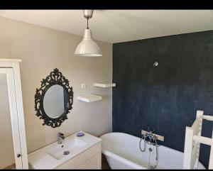 une salle de bain avec une baignoire blanche, un lavabo et un miroir dans l'établissement Les oliviers, à Saint-Didier 10 autres photos