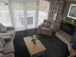 Una sala de estar con un sofá, un televisor y una mesa. en Misty bay, en Tattershall