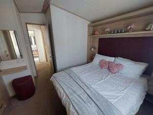 a bedroom with a bed with two hearts on it at Orchid by Davies Caravans on Oakdene Forest Park in Saint Leonards +7 photos