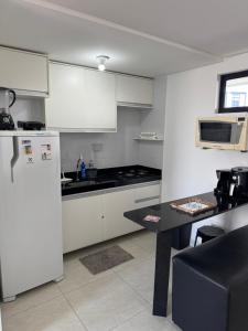 a kitchen with a white refrigerator and a table at FLAT ALTO PADRÃO NO CENTRo in Campina Grande