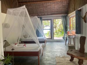 a bedroom with two beds with mosquito nets at Aurora Lodge in Ile aux Nattes