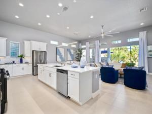 a large kitchen with white cabinets and blue chairs at Luxurious Beach House with heated pool in Marineland +77 photos