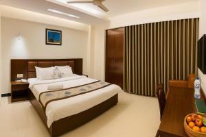 库克斯巴扎Ocean Palace Cox'sBazar的一间卧室配有一张床、一张桌子和一张带一碗水果的桌子。