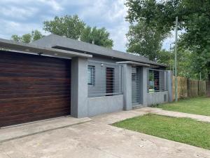 a house with a garage door and a yard at Casa Los Nogales in Roldán