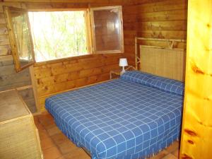 ein blaues Bett in einem Holzzimmer mit Fenster in der Unterkunft Serena Holiday Home in Marina di Camerota