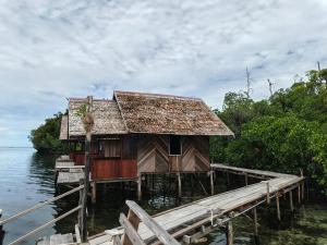 a house on a dock on a body of water at Tapor Pandera Homestay in Besir