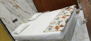 a white bed with a floral pillow on it at N R GUEST ROOMs in Warangal