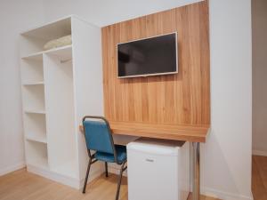 a room with a desk and a tv on a wall at Hotel Raul's in Gaspar