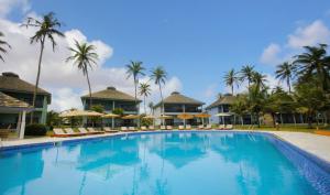 a swimming pool at a resort with palm trees at AnoMansa Beach Resort at Elmina Bay in Elmina