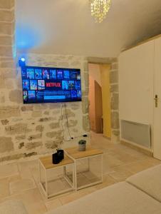 - un salon avec une télévision sur un mur en pierre dans l'établissement Le Mistral - Pont du Gard - Cozy & Intime - WiFi fibre -TV, à Saint-Bonnet-du-Gard