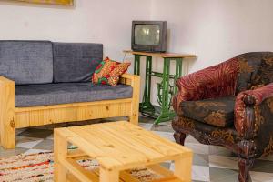a living room with a couch and a chair and a tv at Vintage Room - Nostalgic charm for couples in Gulu