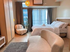 a bedroom with a bed and a chair and a window at Kozy Mood Studio - 19N Renoir in Manila +36 photos