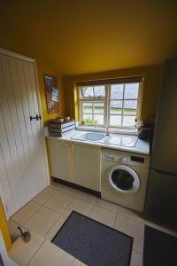 een keuken met een wasmachine en een raam bij Heale Farm Cottage in Trentishoe