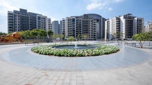 Una fuente en un parque con edificios al fondo. en Habitat Towers, en Sheikh Zayed
