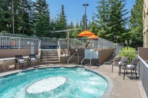 a swimming pool with chairs and an umbrella at Woodrun Lodge 216 | Renovated Ski-In Ski-Out Condo w/ Free Parking, Pool, Hot Tub, & Gym in Whistler
